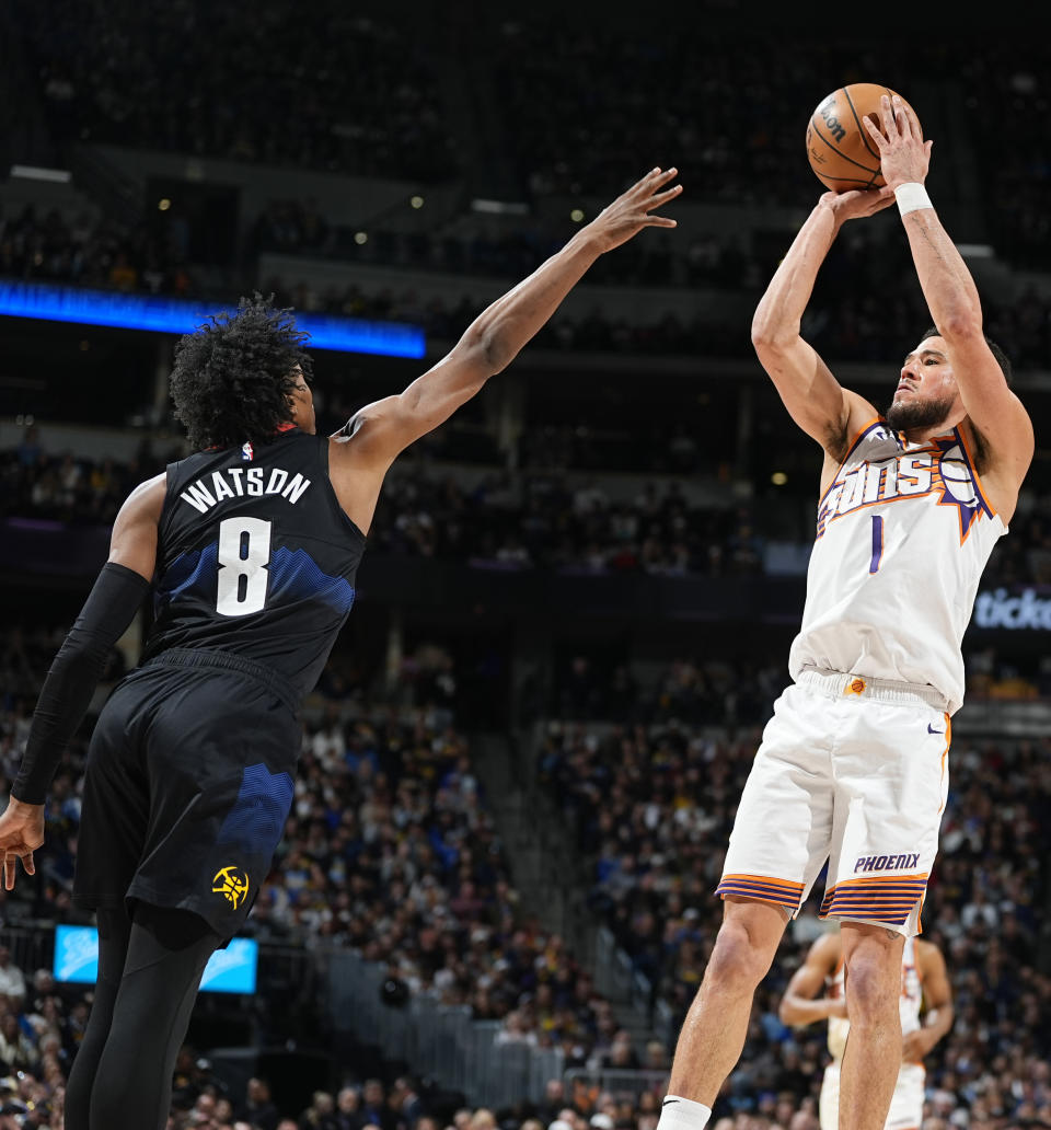 Phoenix Suns guard Devin Booker, right, goes up for a basket over Denver Nuggets forward Peyton Watson during the first half of an NBA basketball game Wednesday, March 27, 2024, in Denver. (AP Photo/David Zalubowski)