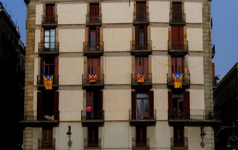 FILE PHOTO: A woman cleans the windows of a house underneath Esteladas (Catalan separatist flags) hanging on balconies at Sant Jaume Square in Barcelona