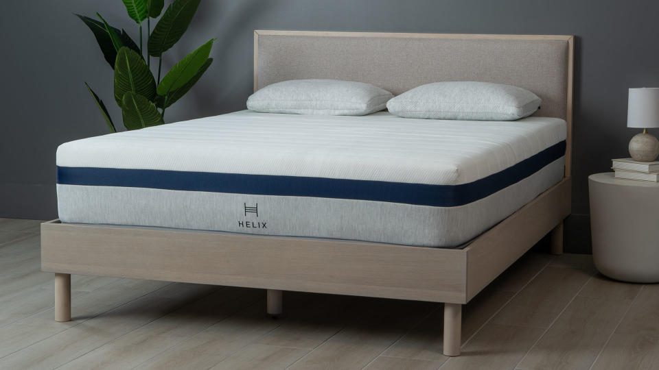 Helix Midnight mattress on a wooden bedframe, against a dark wall