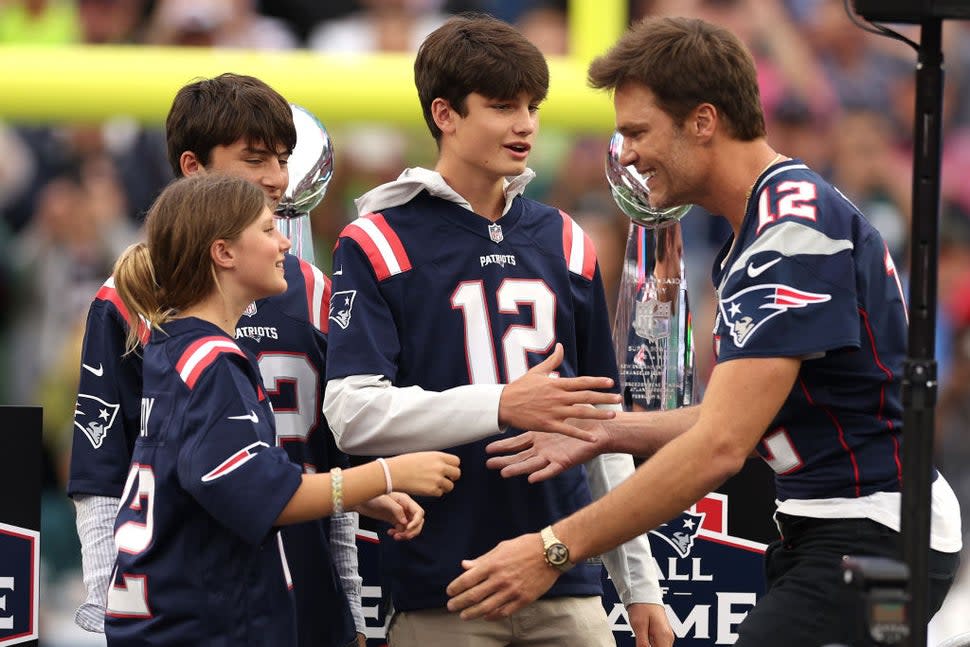 : Former New England Patriots quarterback Tom Brady hugs his daughter, Vivian, while his sons, Benjamin and Jack, look on during a ceremony honoring Brady at halftime of New England's game against the Philadelphia Eagles at Gillette Stadium on September 10, 2023 in Foxborough, Massachusetts.