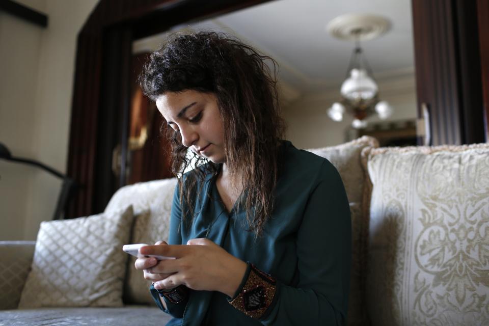 Farah Baker, 16, uses her phone to tweet in her family's home in Gaza City, August 10, 2014. As bombs explode in Gaza, Palestinian teenager Farah Baker grabs her smartphone or laptop before ducking for cover to tap out tweets that capture the drama of the tumult and fear around her. The 16-year-old's prolific posts on Twitter have made her a social media sensation through the month-old conflict. Once a little known high school athlete, Baker's following on the Web site has jumped from a mere 800 to a whopping 166,000. Picture taken August 10, 2014. REUTERS/Siegfried Modola (GAZA - Tags: MEDIA SCIENCE TECHNOLOGY CIVIL UNREST POLITICS CONFLICT)