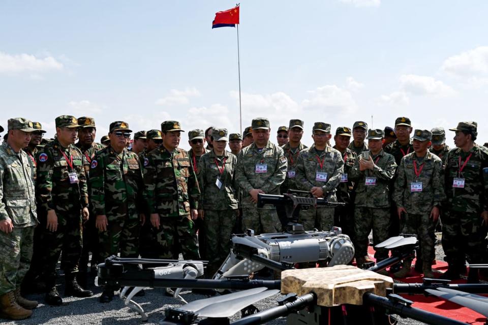 Chinese and Cambodian soldiers attend a demo of robot fighting dogs.