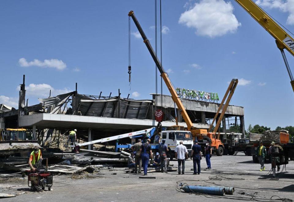 Workers help rescuers to remove rubble of the Amstor mall in Kremenchuk, on June 28, 2022, one day after it was hit by a Russian missile strike, according to Ukrainian authorities. / Credit: GENYA SAVILOV/AFP via Getty Images