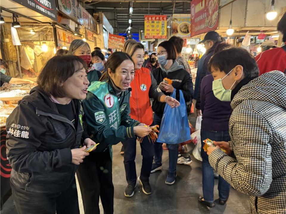 台中五選區立委選情激烈，民進黨候選人莊競程的「牽手」方心慧（左二）與總統府秘書長林佳龍的太太廖婉如（左一）22日下午前往北屯區一點利黃昏市場掃街拜票，「夫人牌」出動大展親和力。（立委莊競程辦公室提供／潘虹恩台中傳真）