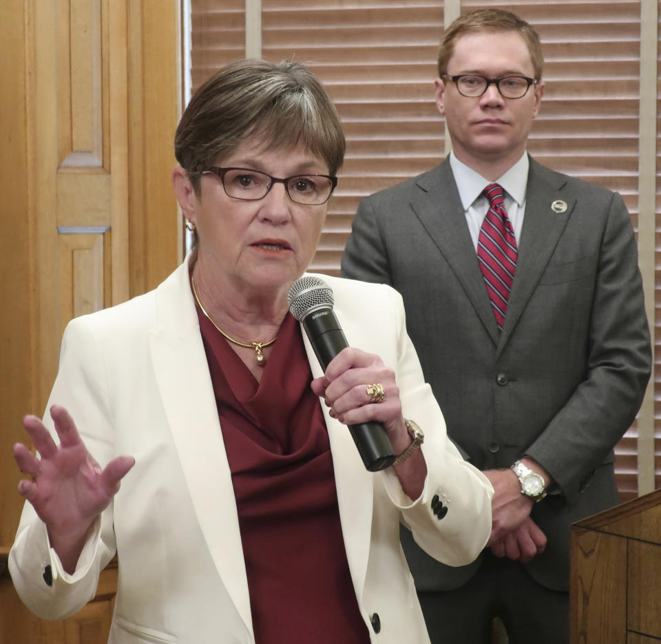 Kansas Gov. Laura Kelly answers questions from reporters after signing her executive order aimed at ending an economic "border war" between her state and Missouri over jobs in the Kansas City area, Friday, Aug. 2, 2019, at the Statehouse in Topeka, Kansas. Standing behind her is Kansas Commerce Secretary David Toland. (AP Photo/John Hanna)
