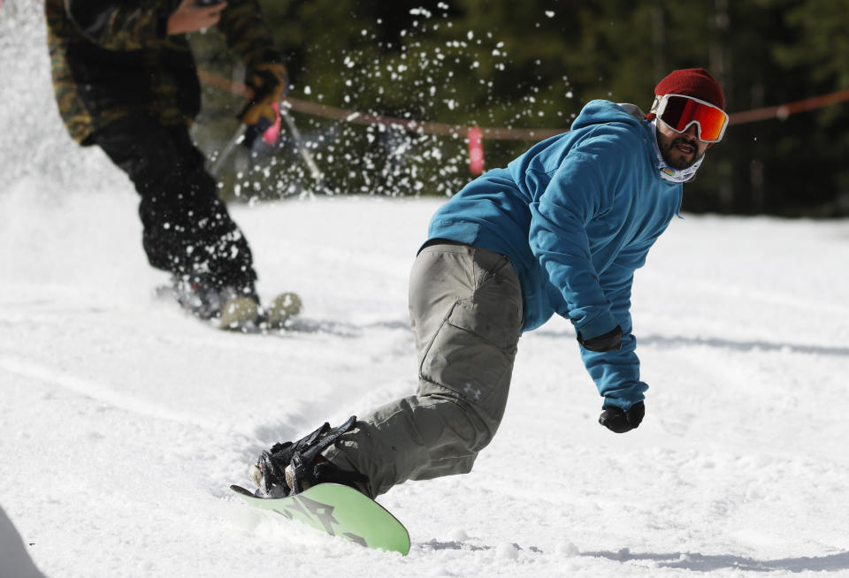 FILE - In this Wednesday, May 27, 2020, file photograph, a snowboarder completes his first run at the reopening of Arapahoe Basin Ski Resort, which closed in mid-March to help in the effort to stop the spread of the new coronavirus in Keystone, Colo. Leaders in the outdoor industry hold hope for a bright future as the virus drives people to seek entertainment in the great outdoors. (AP Photo/David Zalubowski, File)