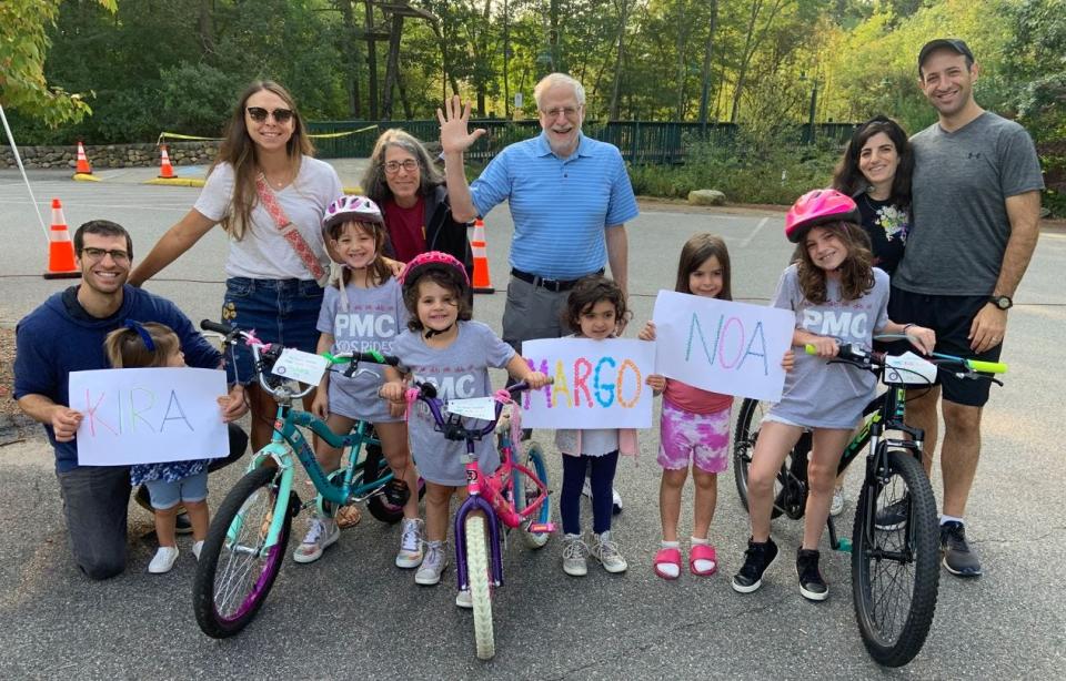 A family holds signs in support of their rider at the 2022 Tri-Town Pan Mass Challenge Kids Ride.