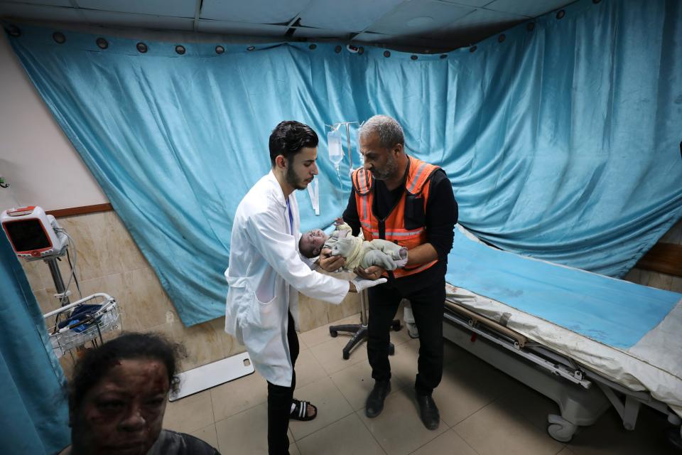 A Palestinian medic holds a child wounded in Israeli air strike on the Gaza Strip in Deir el-Balah on Oct. 22, 2023.