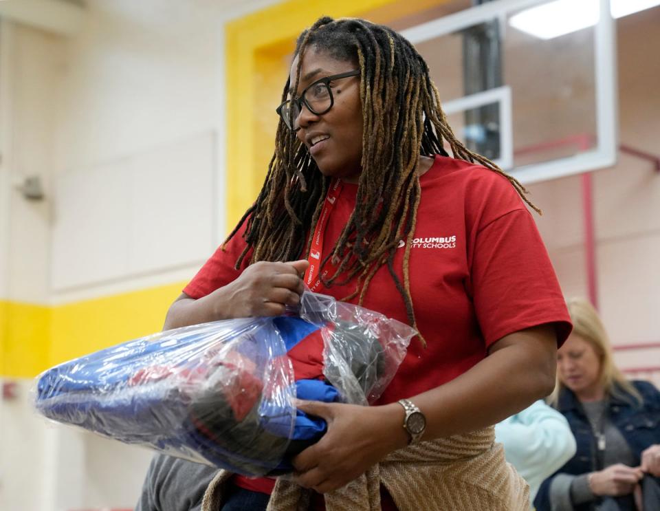 Lee Cole, executive director of Columbus City Schools Community Engagement and Partnerships, unpacks winter coats during a distribution event at Burroughs Elementary School.