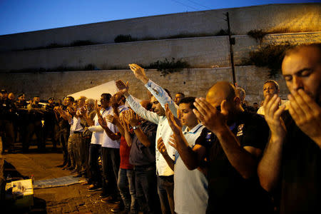 Israeli border police stand guard a Palestinian men take part in evening prayers outside the Lion's Gate of Jerusalem's Old City July 24, 2017.REUTERS/Ammar Awad