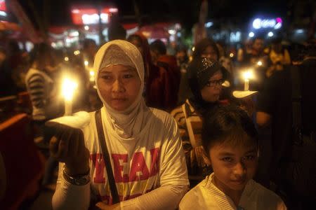 Indonesians hold up candles during a candle light vigil for the victims of AirAsia flight QZ8501 at Surabaya December 31, 2014. REUTERS/Athit Perawongmetha