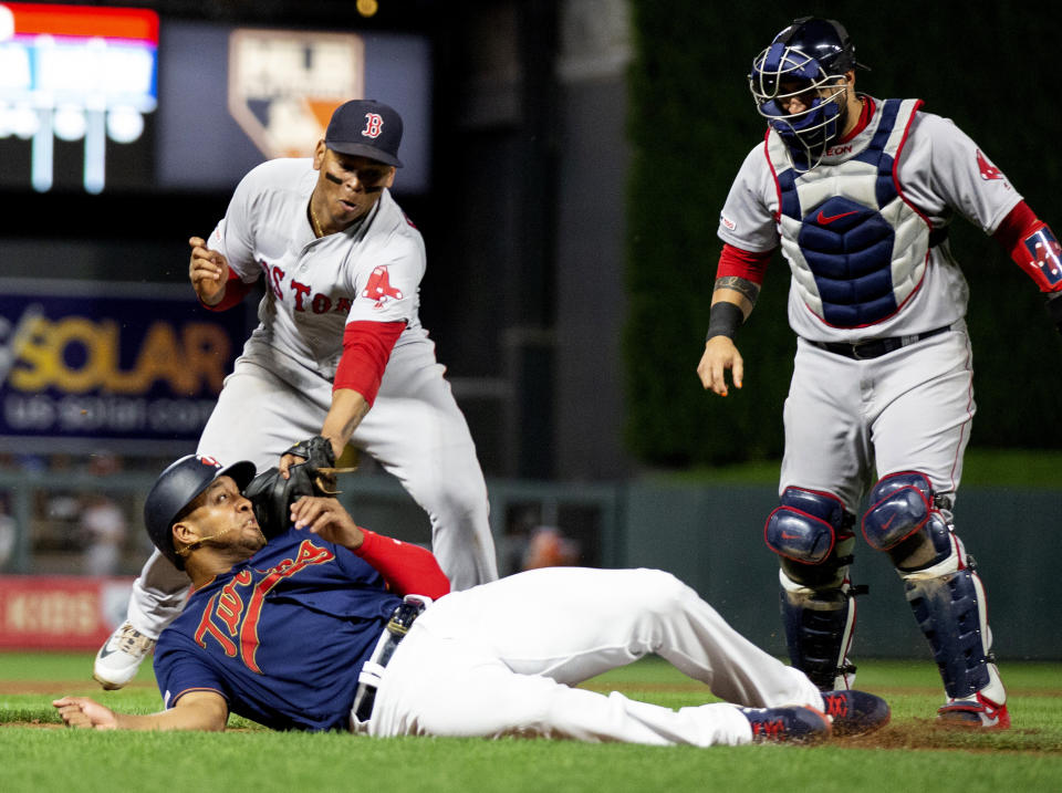 Minnesota Twins' Jonathan Schoop, bottom left, is tagged out by Boston Red Sox third baseman Rafael Devers, top left, while Red Sox catcher Sandy Leon looks on in the eighth inning of a baseball game Monday, June 17, 2019, in Minneapolis. (AP Photo/Andy Clayton- King)