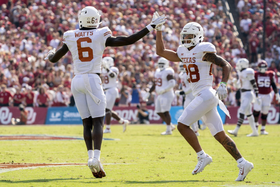 Texas defensive backs Ryan Watts (6) and Jerrin Thompson (28) celebrate a stop during the first half of an NCAA college football game against Oklahoma at the Cotton Bowl, Saturday, Oct. 8, 2022, in Dallas. (AP Photo/Jeffrey McWhorter)