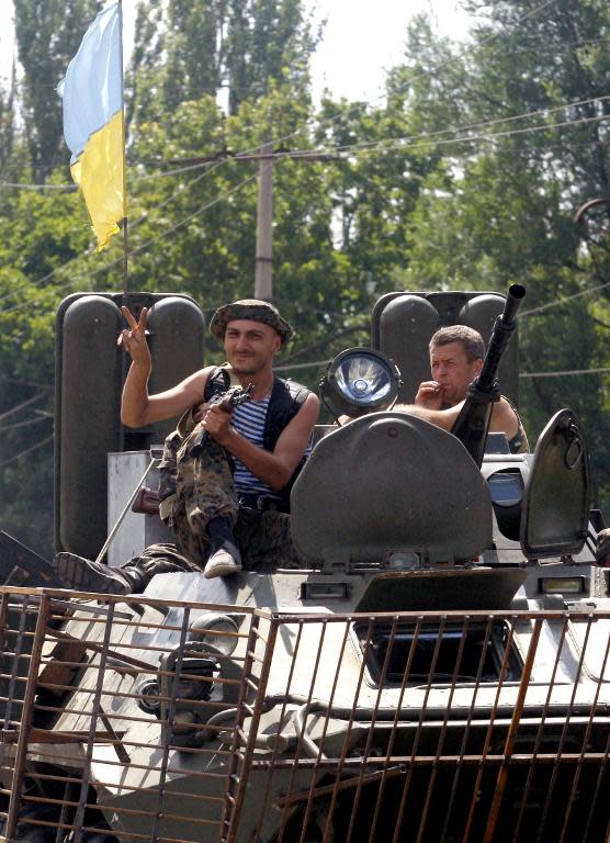 Ukrainian servicemen greet people near the eastern city of Kramatorsk, as they sit on an armoured personnel carrier (APC) on the road to Donetsk, on August 5, 2014