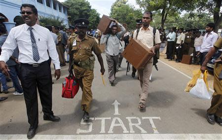 Polling officers carrying ballot boxes walk with police officers as they prepare to go to their polling centres ahead of first provincial polls in 25 years in Jaffna, a former war zone in northern Sri Lanka, about 400 kilometres (249 miles) north of Colombo September 20, 2013. REUTERS/Dinuka Liyanawatte