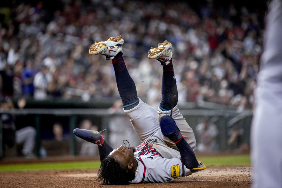 Atlanta Braves' Ozzie Albies rolls to a stop after scoring against the Washington Nationals during the third inning of a baseball game at Nationals Park, Thursday, Sept. 21, 2023, in Washington. (AP Photo/Andrew Harnik)