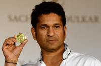 Indian cricketer Sachin Tendulkar displays a limited edition 10 gram gold coin with an embossed image of himself after unveiling it on Akshaya Tritiya in Mumbai on May 13, 2013. A total of 100, 000 limited edition 10 gram Tendulkar Gold coins priced at INR 34,000 (USD 618) will be available for both online purchase and at retail stores of leading jewellers across the country. Akshaya Tritiya is considered to be an auspicious day in the Hindu calendar to buy valuables and people generally flock to buy gold on this day in the belief that it will increase their wealth. AFP PHOTO/ Indranil MUKHERJEE