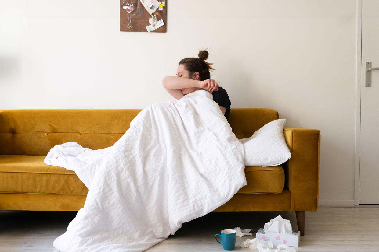 A woman feeling sick in her living room. Getty Images/Roos Koole