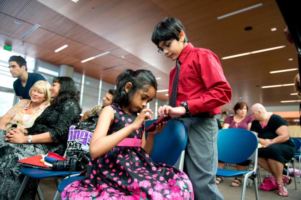 Tiara Abraham, 7, plays a game on a smart phone with her brother Tanishq Abraham, 9, who was inducted in the international honor society Phi Theta Kappa on May 3, 2013 at American River College. Tanishq is the youngest student at the school.