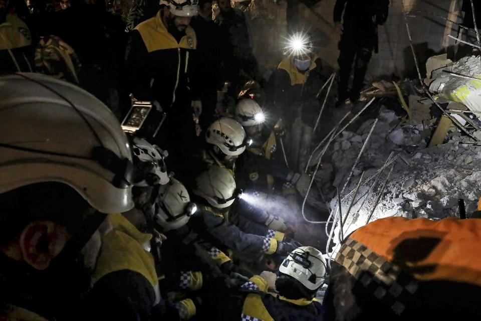 In this photo provided by the Syrian Civil Defense White Helmets, which has been authenticated based on its contents and other AP reporting, Syrian White Helmet civil defense workers search for residents among the debris of a collapsed building on the southern edge of the city of Idlib, Syria, Wednesday, Feb. 9, 2022. The White Helmets said Thursday the building collapsed in northwest Syria leaving a woman and three of her children dead while her husband and three other children were pulled out alive. (Syrian Civil Defense White Helmets via AP)