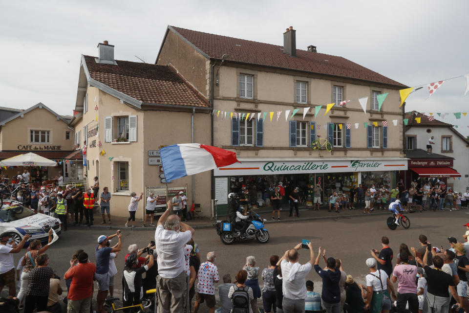 A man waves the French flag as France's Thibaut Pinot passes through his hometown Melisey during stage 20 of the Tour de France cycling race, an individual time trial over 36.2 kilometers (22.5 miles), from Lure to La Planche des Belles Filles, France, Saturday, Sept. 19, 2020. (AP Photo/Thibault Camus)