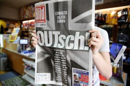 A man holds up the German newspaper Bild with the titel "OUTsch!", for the camera, in Berlin, Germany, June 25, 2016. REUTERS/Axel Schmidt