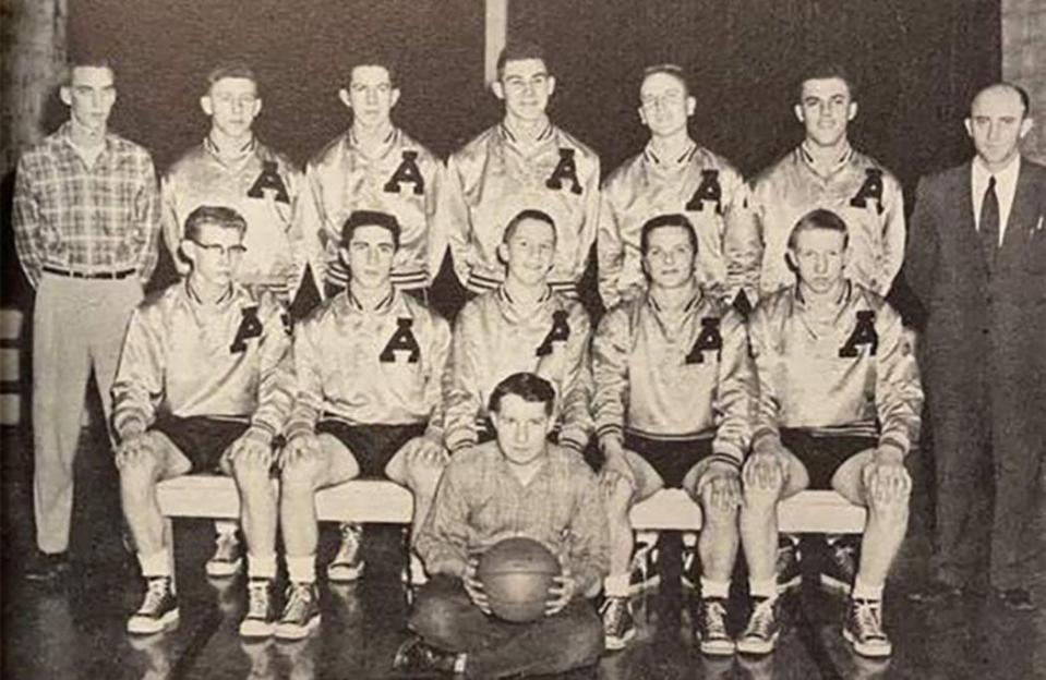 The Alfordsville High School basketball team: Butch Canary is second player seated from the left. Coach Kenny Hudson is standing at left. Wig Canary, principal and father of Butch, is standing right.