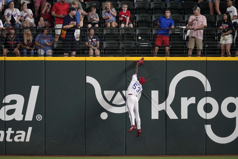 Fans, top, look on as Texas Rangers right fielder Adolis Garcia (53) makes a leaping attempt to reach a solo home run ball hit by Houston Astros' Mauricio Dubon in the ninth inning of a baseball game, Monday, Sept. 4, 2023, in Arlington, Texas. (AP Photo/Tony Gutierrez)