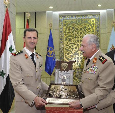 Syria's President Bashar al-Assad (L) receives a gift from Syrian Defense Minister General Ali Habib during a dinner in honor of army officers on the 65th Army Foundation anniversary in Damascus August 1, 2010. REUTERS/Sana
