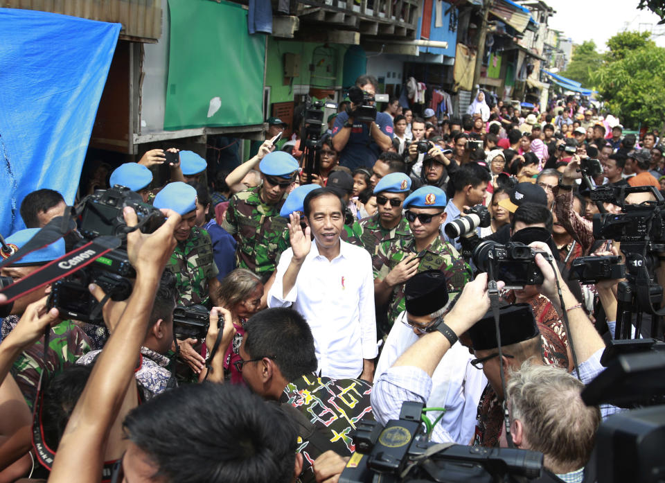 Incumbent Indonesian President Joko Widodo, center, waves to reporters as he leaves after declaring his victory in the country's presidential election, at a slum in Jakarta, Indonesia, Monday, Tuesday, May 21, 2019. Widodo has been elected for a second term, official results showed, in a victory over a would-be strongman who aligned himself with Islamic hard-liners and vowed Tuesday to challenge the result in the country's highest court. (AP Photo/Dita Alangkara)