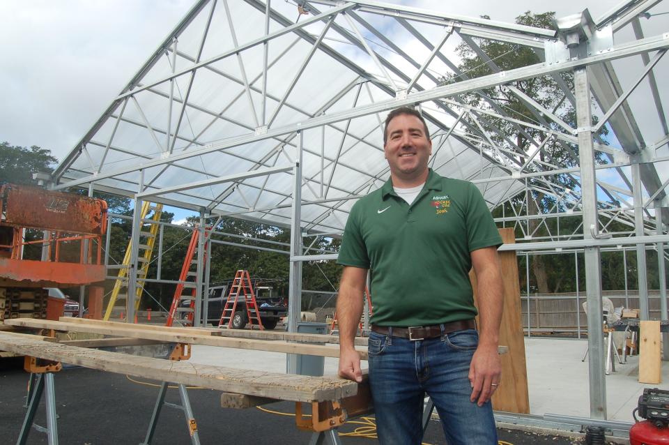 Josh Wile, co-owner of the Agway of Cape Cod store in Orleans, stands in front of a new greenhouse.