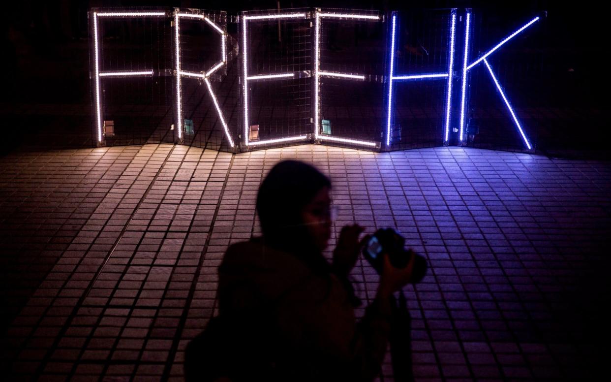 Pro-democracy protesters take photos of a 'Free HK' light display at a gathering in Edinburgh Place in the Central district of Hong Kon - AFP