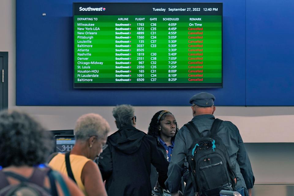 Southwest Airline passengers check into a ticket counter near a sign that shows canceled flights at the Tampa International Airport Tuesday, Sept. 27, 2022, in Tampa, Fla. The airport is closing at 5 pm EST ahead of Hurricane Ian.