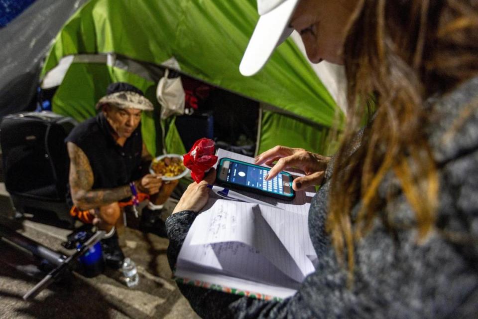 A Hermanos de la Calle volunteer takes down the information of a unhoused man in hopes of getting him into a shelter during a food distribution event on NW 17th Street in Miami, Florida, on Friday, December 22, 2023. D.A. Varela/dvarela@miamiherald.com