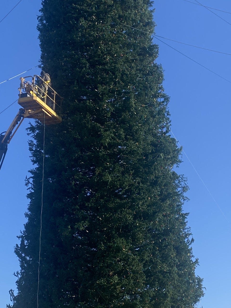 Crew members use ornaments and lights to decorate the towering Christmas tree in 2022 to prepare for The One tree-lighting ceremony in Enid.