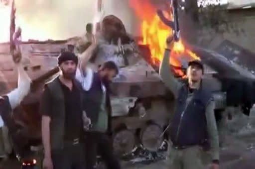An image grab taken from a video uploaded on YouTube allegedly shows Syrian rebels raising their guns next to a burning tank after their confrontation with Syrian Army on the outskirts of Duma. President Bashar al-Assad has dismissed accusations his government had any role in the brutal Houla massacre, as he charged forces outside Syria of plotting to destroy the country
