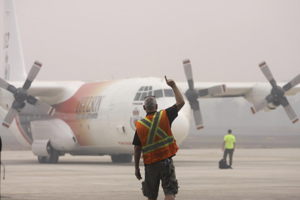 A ground crew gives a hand signal at a C-130 cargo plane of Australia's New South Wales Rural Fire Service as it prepares for a water bombing mission to help battling wildfires, at Sultan Mahmud Badaruddin in Palembang, South Sumatra, Indonesia.