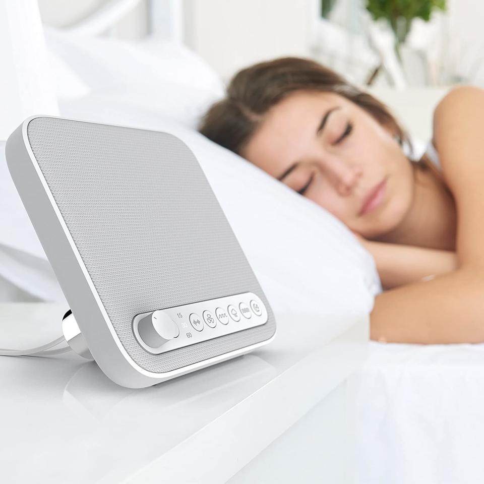 Sleep therapy sound machine placed on bedside table in front of sleeping model 