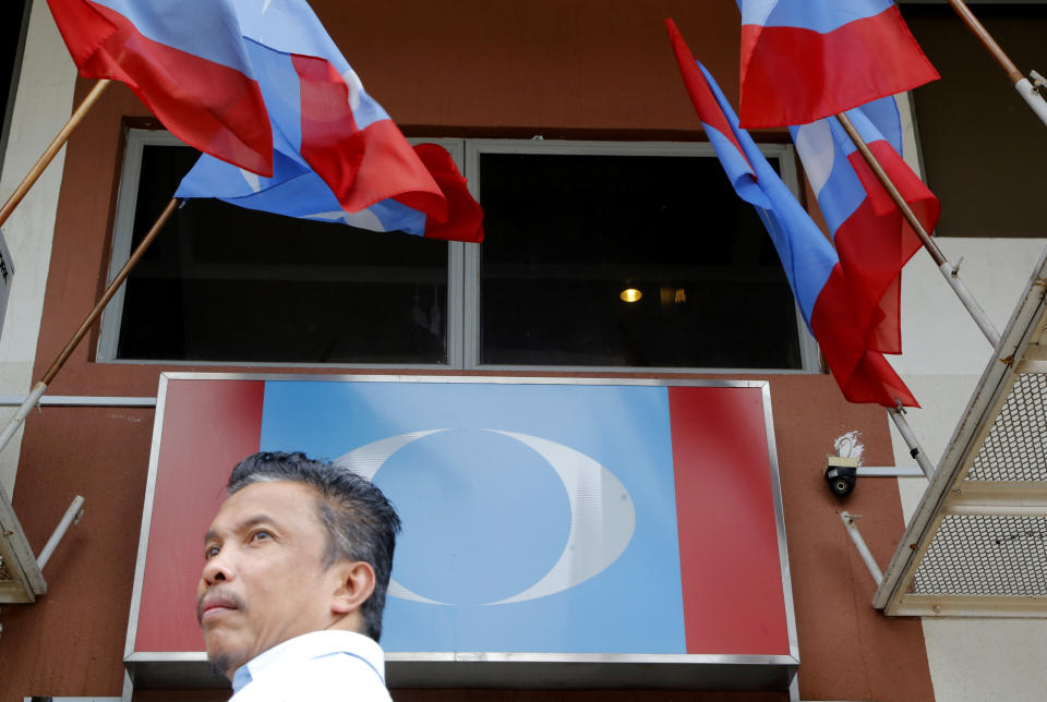 A Malaysian man walks beneath flags of Anwar's Ibrahim's People's Justice Party in Petaling Jaya, Malaysia, Wednesday, Sept. 12,2018. Officials say Malaysia's prime minister-in-waiting Anwar will contest a by-election that will pave the way for his return to active politics. Lawmaker Danyal Balagopal Abdullah said Wednesday, Sept. 12, 2018, he has resigned as a member of Parliament in Port Dickson, a southern coastal town, to make way for Anwar's comeback. (AP Photo/Yam G-Jun)