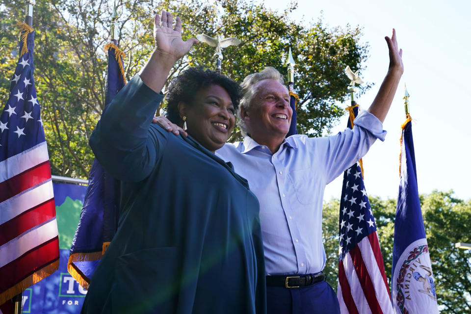 FILE - In this Monday, Oct. 17, 2021, file photo, political activist Stacey Abrams, left, waves to the crowd with Democratic gubernatorial candidate, former Virginia Gov. Terry McAuliffe, right, during a rally in Norfolk, Va. McAuliffe won Virginia's 2013 governor's race by embracing his own brand of personal politics that rely on decades-old friendships, back-slapping charisma and tell-it-like-it-is authenticity. (AP Photo/Steve Helber, File)