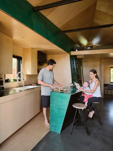 The couple, both architects, and their youngest child surround the kitchen island, which is canted to maximize interior space.