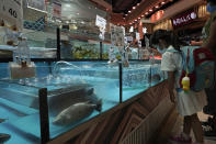 A girl stands next to the fish from MoVertical Farm at a supermarket in Hong Kong Thursday, Sept. 24, 2020. Operating on a rented 1,000 square meter patch of wasteland in Hong Kong's rural Yuen Long, Arthur Lee's MoVertical Farm utilizes around 30 of the decommissioned containers, to raise red water cress and other local vegetables hydroponically, which eliminates the need for soil. A few are also used as ponds for freshwater fish, with the bounty sold to local supermarkets in this crowded city of 7.5 million that is forced to import most of its food. (AP Photo/Kin Cheung)