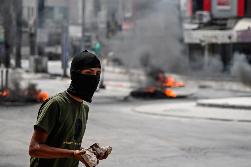 PHOTO: A masked Palestinian youth holds stones in his hands during confrontations with Israeli troops stormed the northern occupied West Bank city of Jenin, on May 22, 2024. (Afp Contributor#afp/AFP via Getty Images)