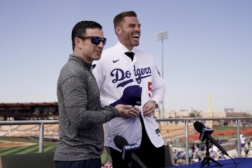 Dodgers first baseman Freddie Freeman laughs as he puts on a Dodgers jersey next to Andrew Friedman.