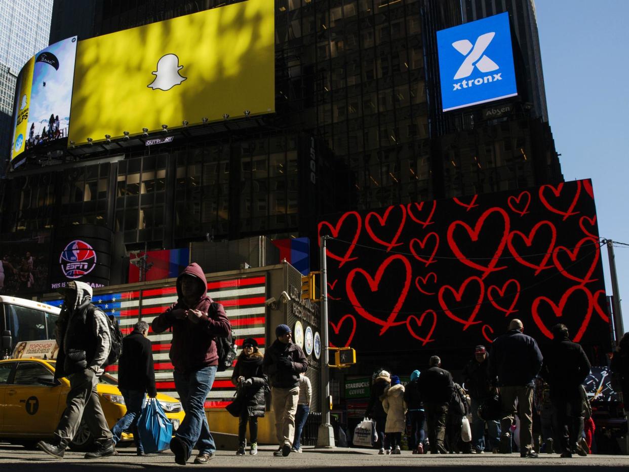 Pedestrians cross the street below a billboard displaying the logo of Snapchat above Times Square in New York March 12, 2015: REUTERS/Lucas Jackson