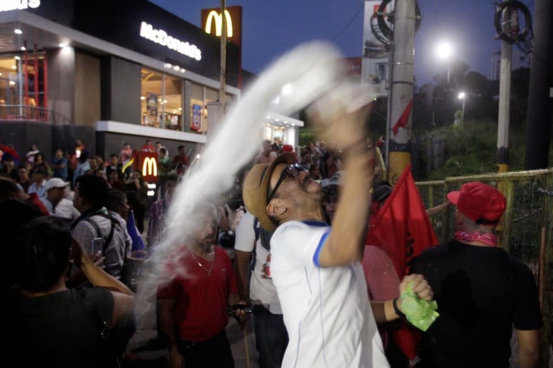 A demonstrator throws a plastic bag with white powder during a protest against the government of president Juan Orlando Hernandez, whose brother Juan Antonio "Tony" Hernandez was found guilty of U.S. drug trafficking charges, in Tegucigalpa