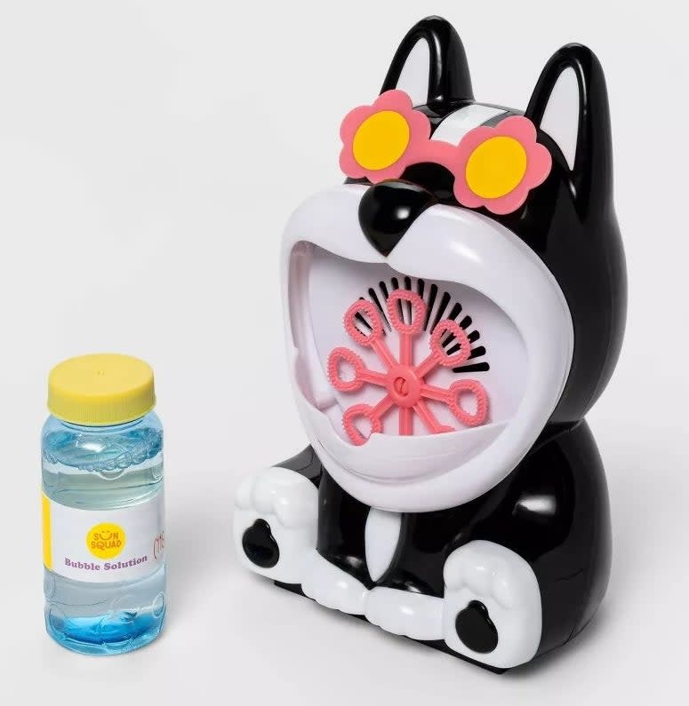 A plastic black and white dog with a bubble maker in its open mouth and a jar of bubble solution