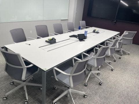 A white conference table with twelve gray and white swivel chairs.