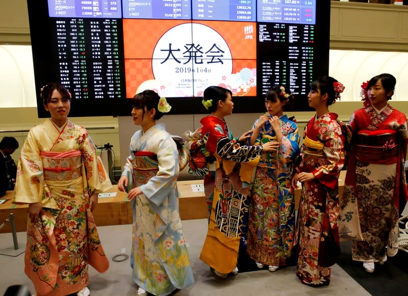 FILE PHOTO: Women, dressed in ceremonial kimonos, chat in front of an electronic board showing stock prices after the New Year opening ceremony at the Tokyo Stock Exchange (TSE), held to wish for the success of Japan's stock market, in Tokyo