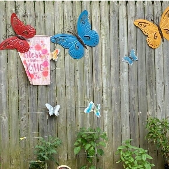 Garden wall with a variety of butterfly decorations and a "Bless Our Home" sign